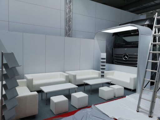 Moderne Lounge mit weißen Sofas, Tischen und Regalen, unvollständig aufgebaut.